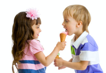 girl shares, gives or feeds boy with her ice cream in studio isolated
